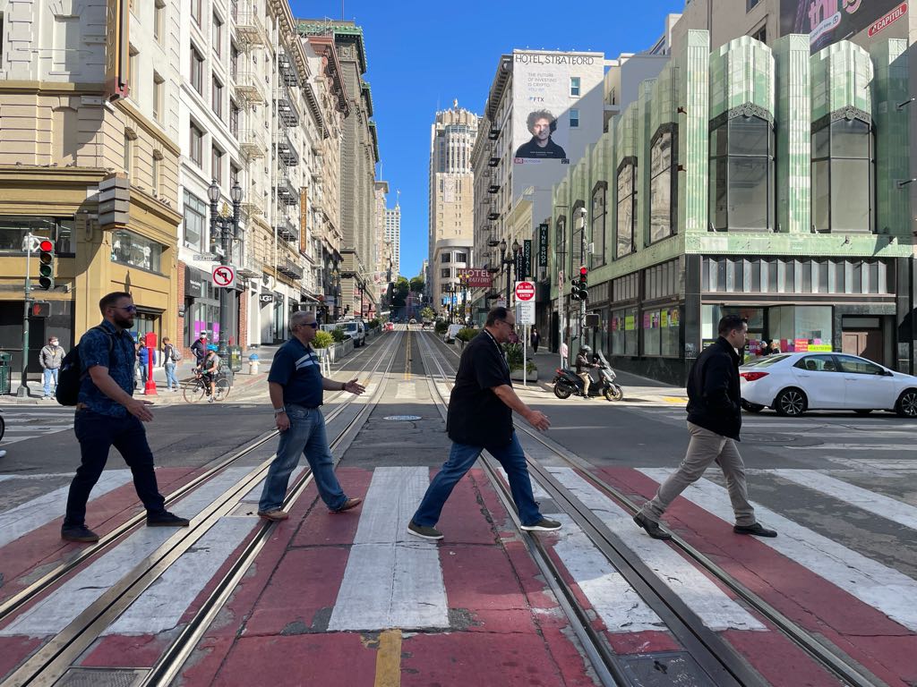A group of coworkers reenacts the iconic Abbey Road crossing in downtown San Francisco during a team building activity with Adventure Games Inc, known for delivering the best team building experiences in San Francisco.
