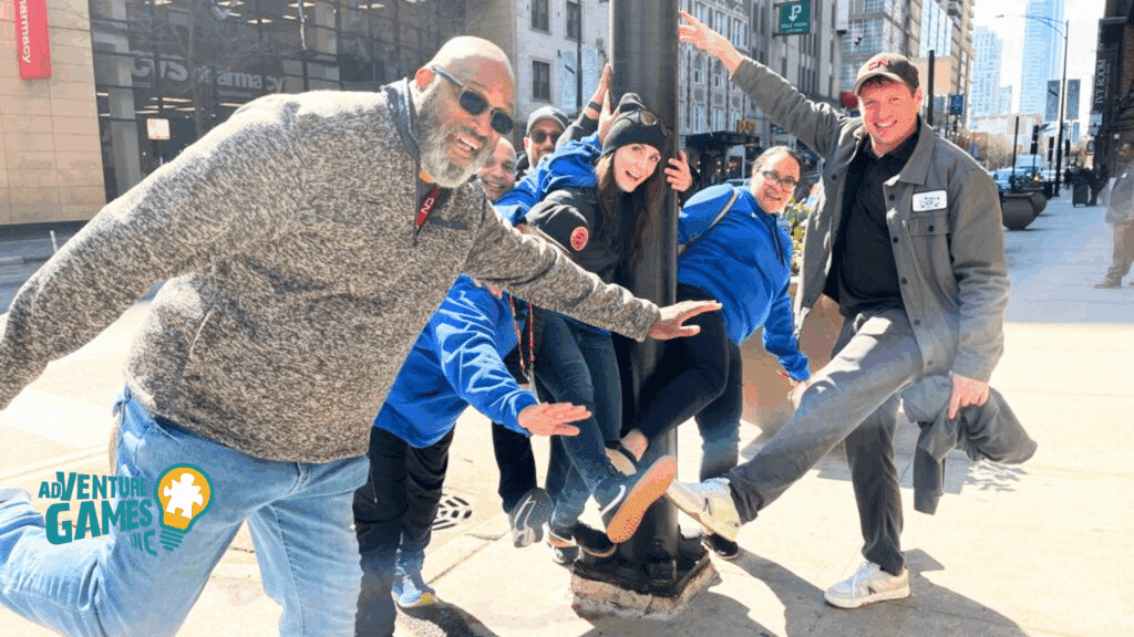 Group of coworkers in bright blue and gray jackets posing mid-action on a city sidewalk during a high-energy team-building scavenger hunt by Adventure Games Inc.
