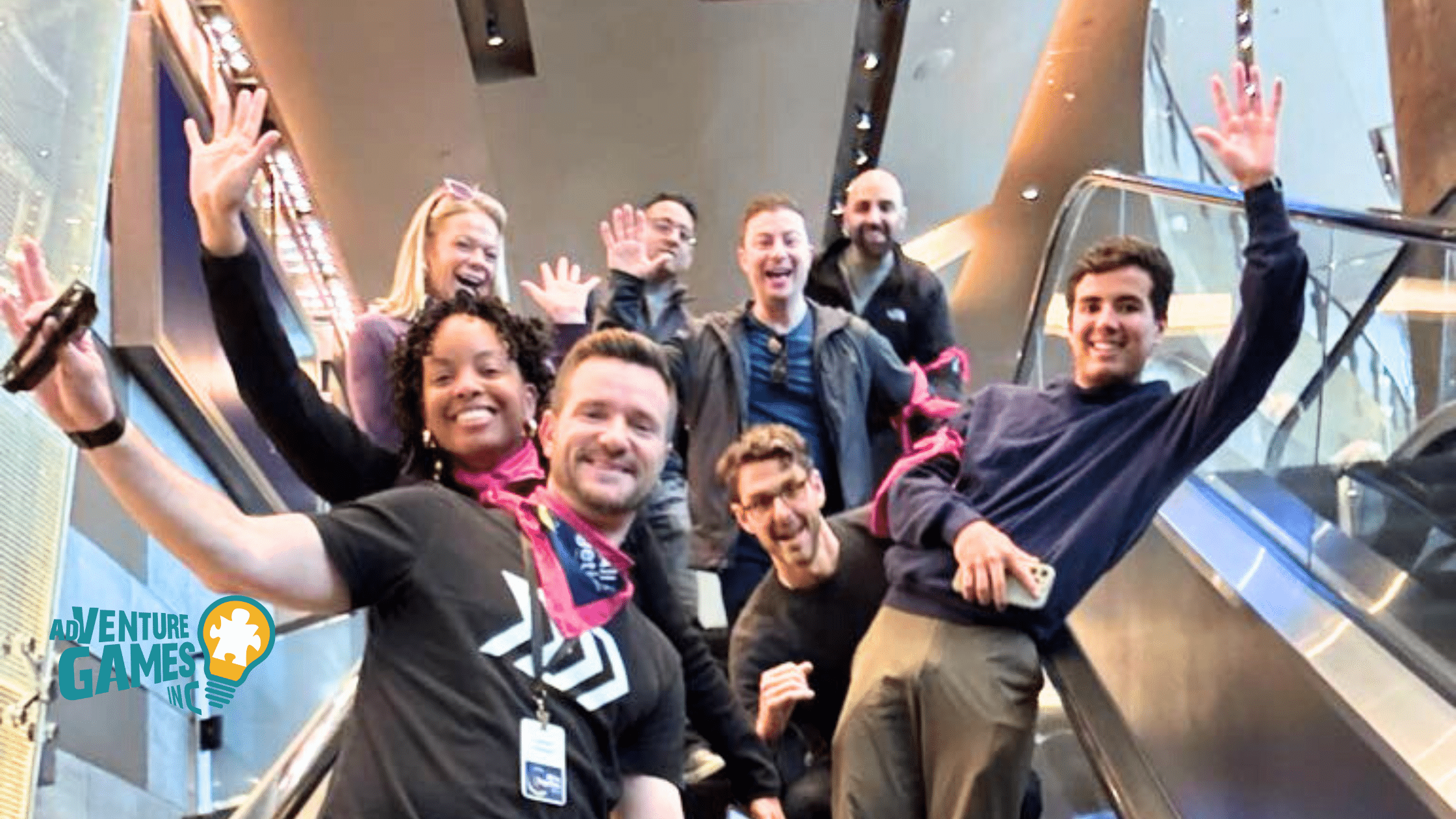 A lively group of coworkers waves from an escalator during a fast-paced, citywide team-building event organized by Adventure Games Inc.