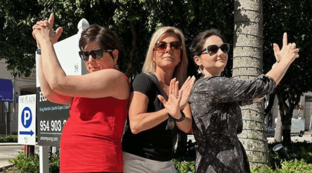 Three coworkers strike playful secret agent poses on a sidewalk during a SpyGame team building challenge led by Adventure Games Inc.