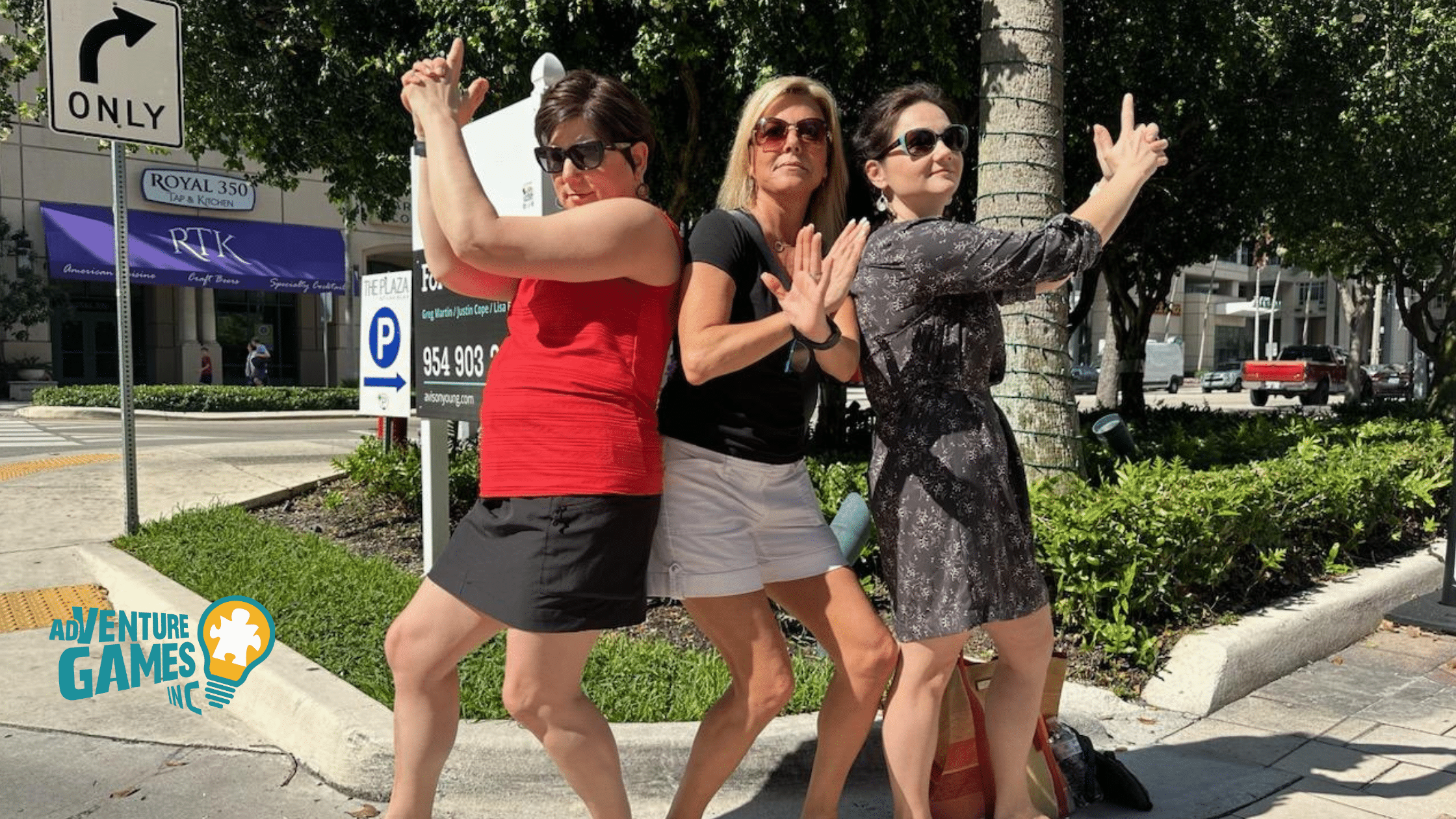 Three coworkers strike playful secret agent poses on a sidewalk during a SpyGame team building challenge led by Adventure Games Inc.