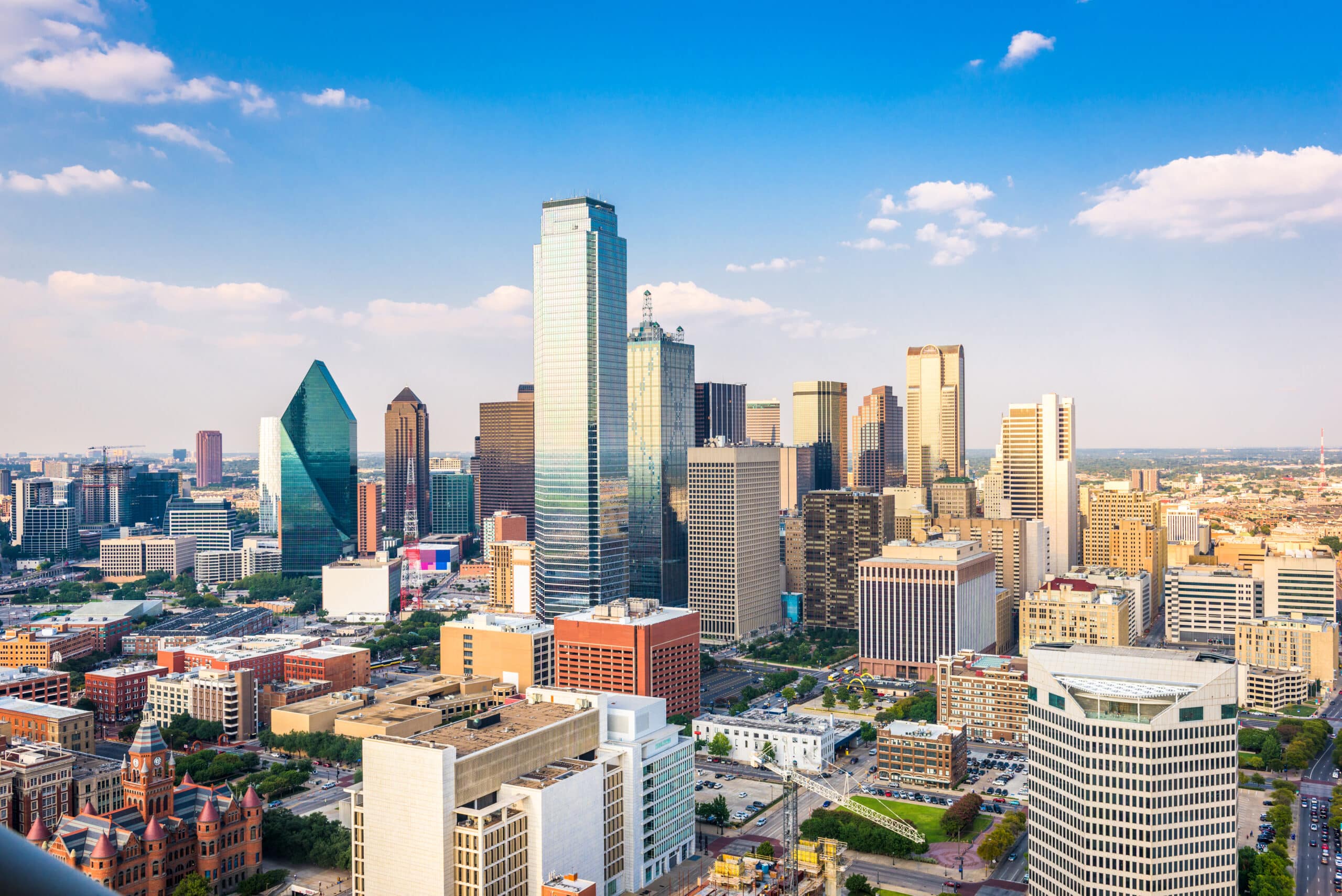 Dallas TX City Skyline on a beautiful sunny day with a bright blue sky with a few white fluffy clouds floating in the distance.