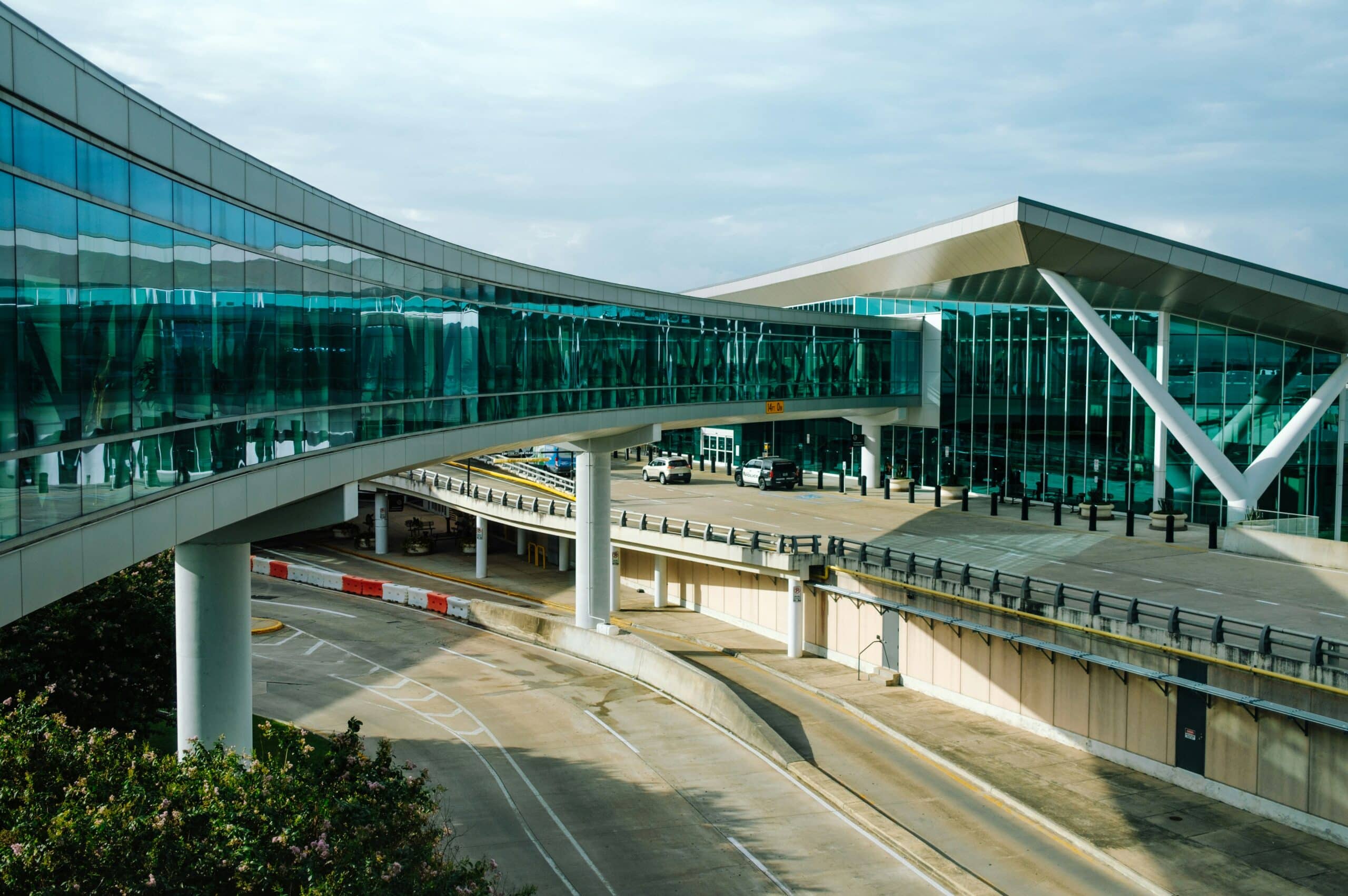Modern glass terminal building at Houston airport with elevated roadway and covered passenger drop-off area