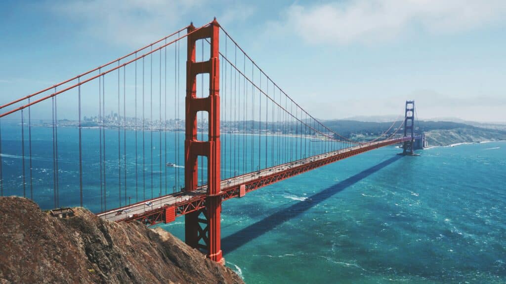 Looking down at the Golden Gate Bridge on a sunny day with light clouds and a beautiful blue sky above.